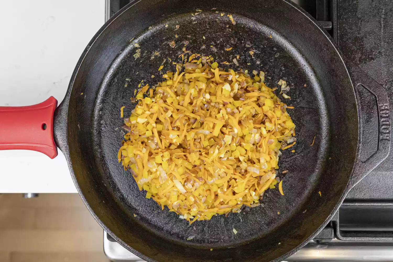 Overhead view of onions, pepper, and spices cooking in a cast iron pan. 